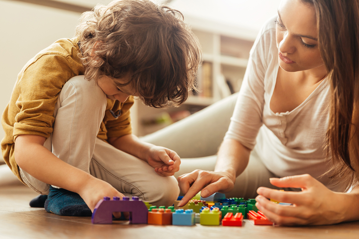 Close up of a young woman and her son playing with colourful blocks